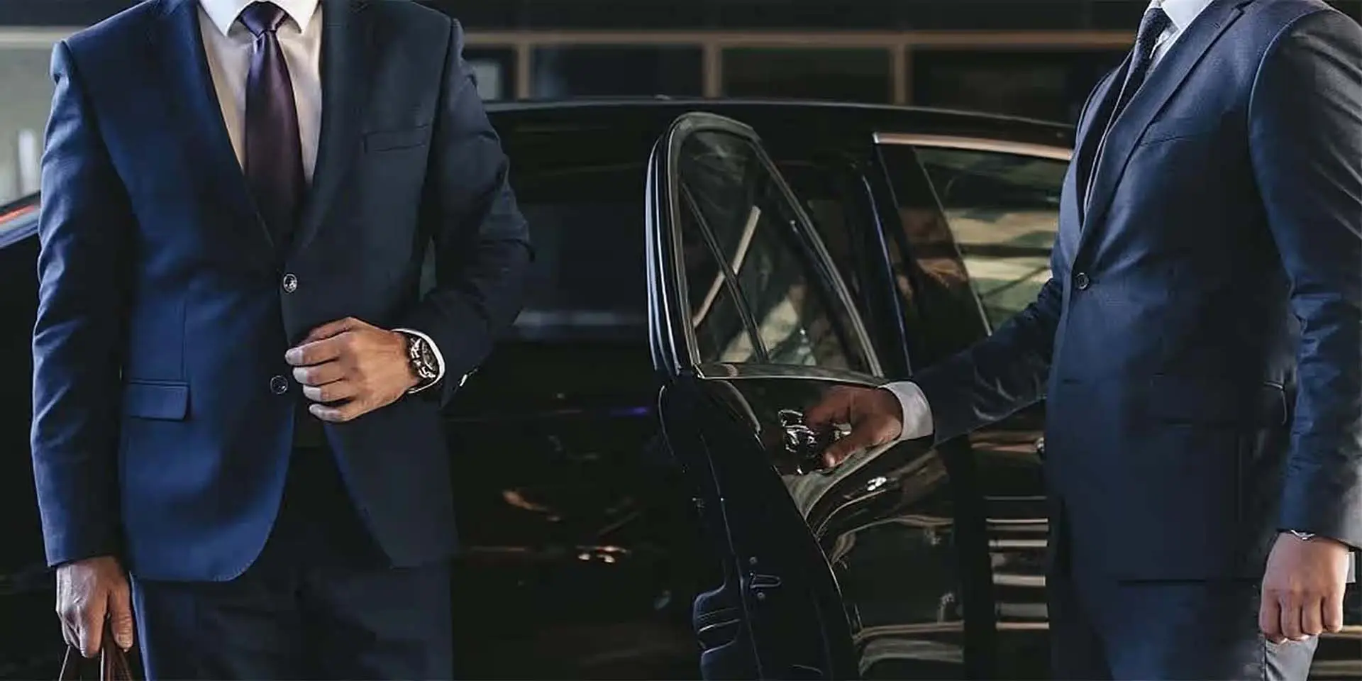 Chauffeur opening the door of a black car for guests arriving at a Boston holiday party